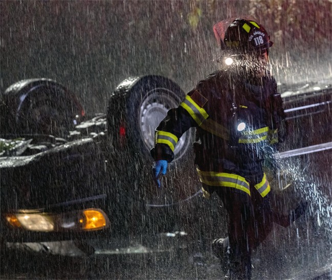 Sous une pluie abondante, l'auxiliaire médical et le pompier, Howie Han, intervient sur le terrain.