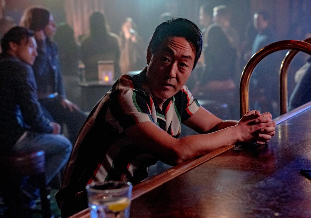 Howie Han est assis dans un bar pour boire un verre en regardant autour de lui.